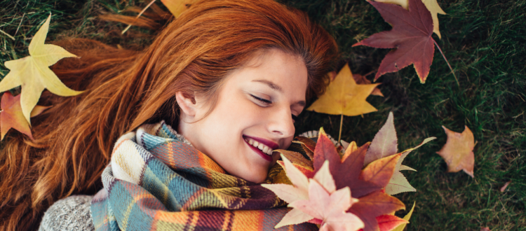 Red-haired woman lying on the grass, enjoying the autumn weather