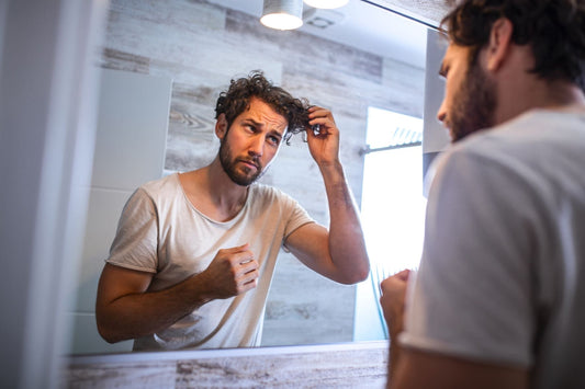 Man with curly hair examining his hairline in the mirror