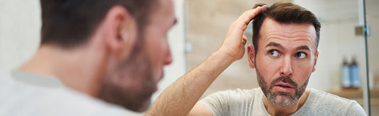 Man examining his side hair in the mirror