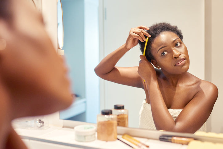 Woman combing her curly hair while looking in the mirror