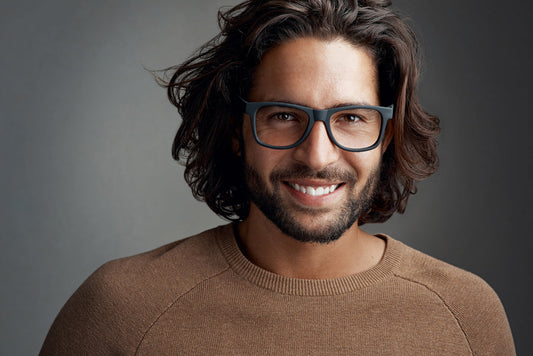 Smiling man with wavy medium brown hair wearing glasses