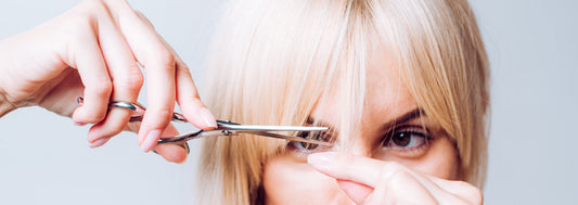 Woman trimming the ends of her blonde hair