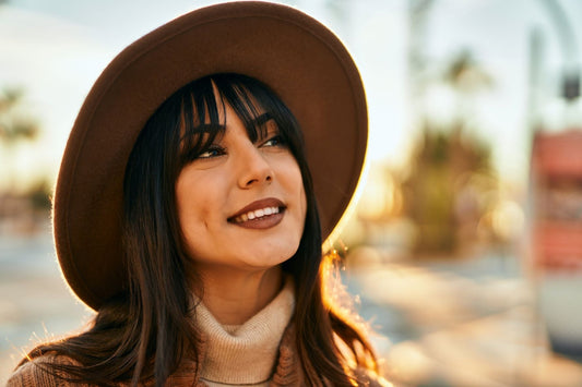 Smiling woman with long brunette hair wearing a hat