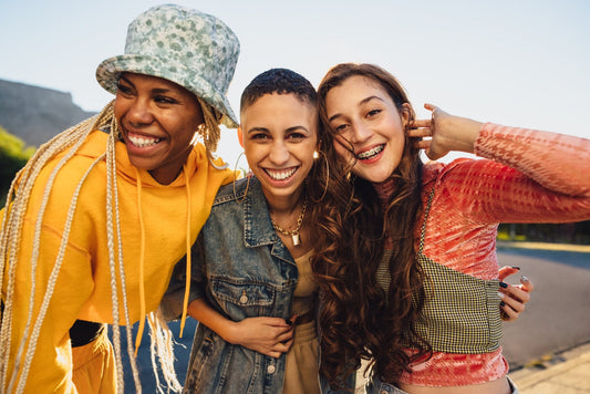 Three women with different hairstyles smiling outdoors