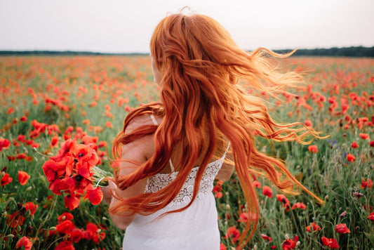 Woman with wavy red hair in a field of flowers