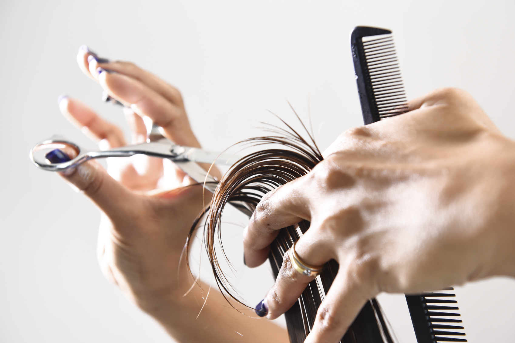 Hand with a comb cutting hair of woman
