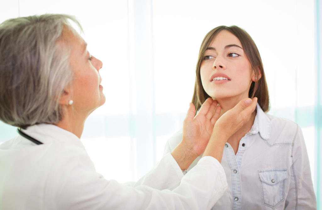 Doctor examines young female patient's thyroid hypothyroidism hair loss Toppik hair blog